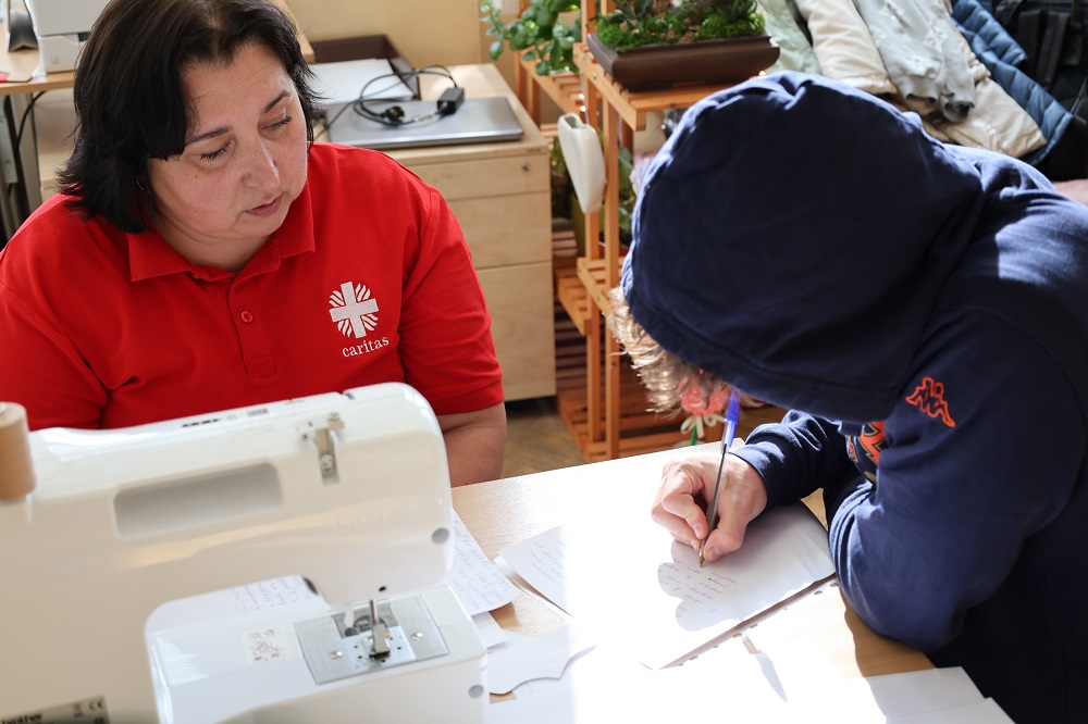 Žena pomáha cidzincom s s vypísaním žiadosti aj so životopisom