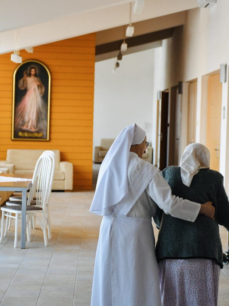 mníška pomáha s chôdzou staršia pani
