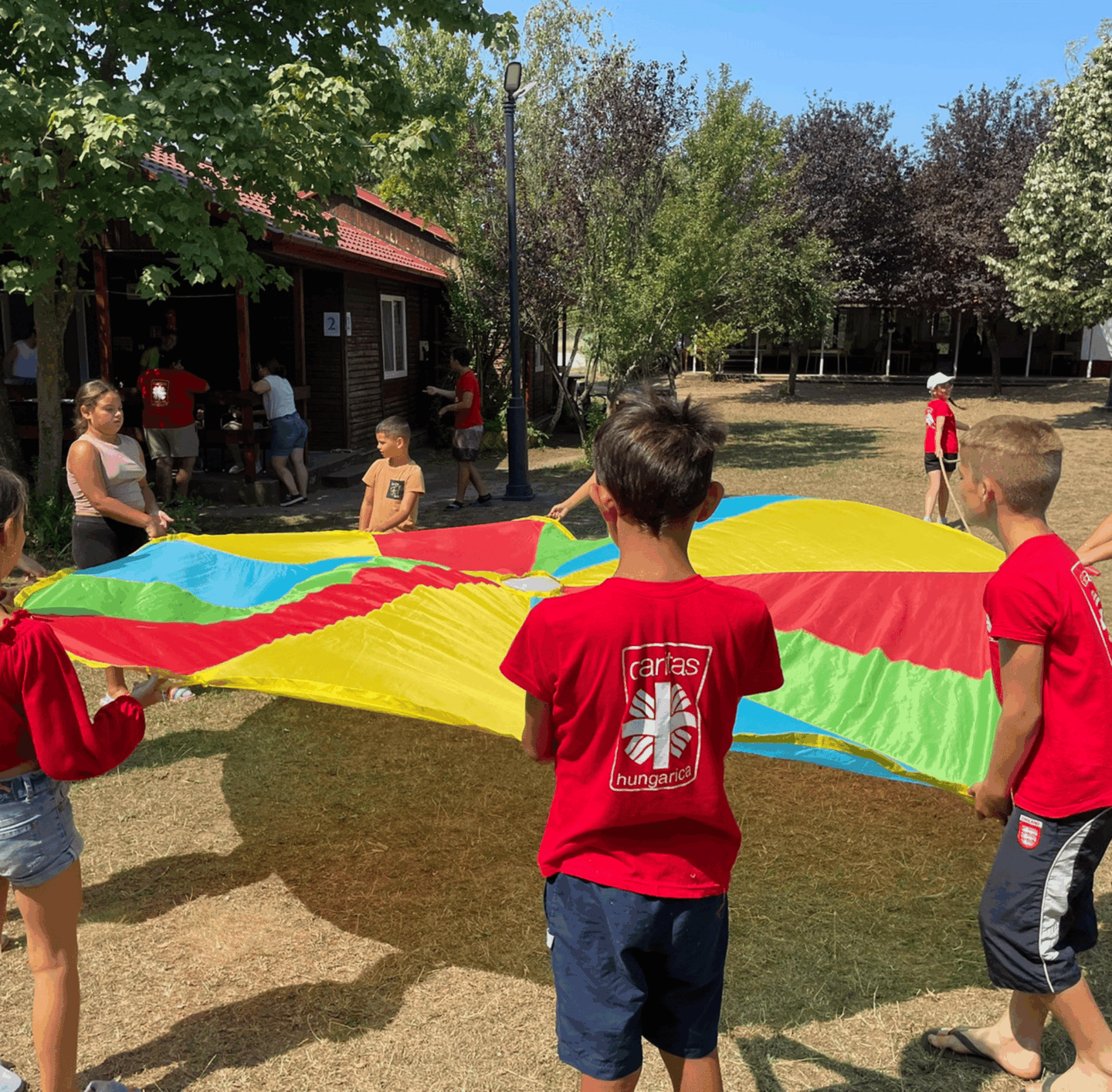deti v osade sa hrajú s farebnou plachtou