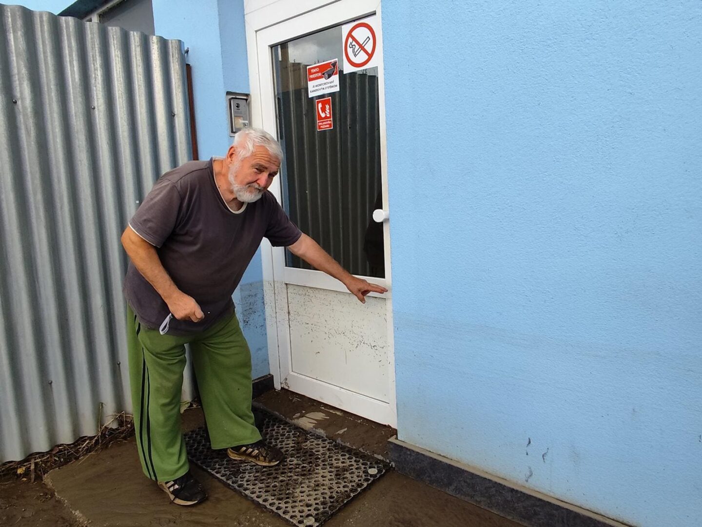 Muž ukazuje, kam až siahala voda pri povodni