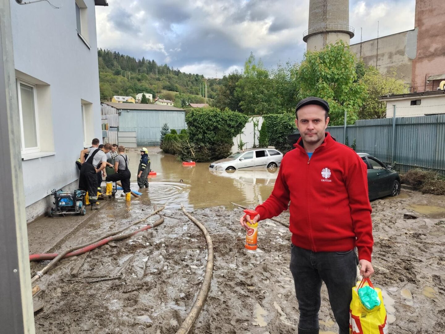 pracovník charity ide pomáhať upratovať škody spôsobené povodňami