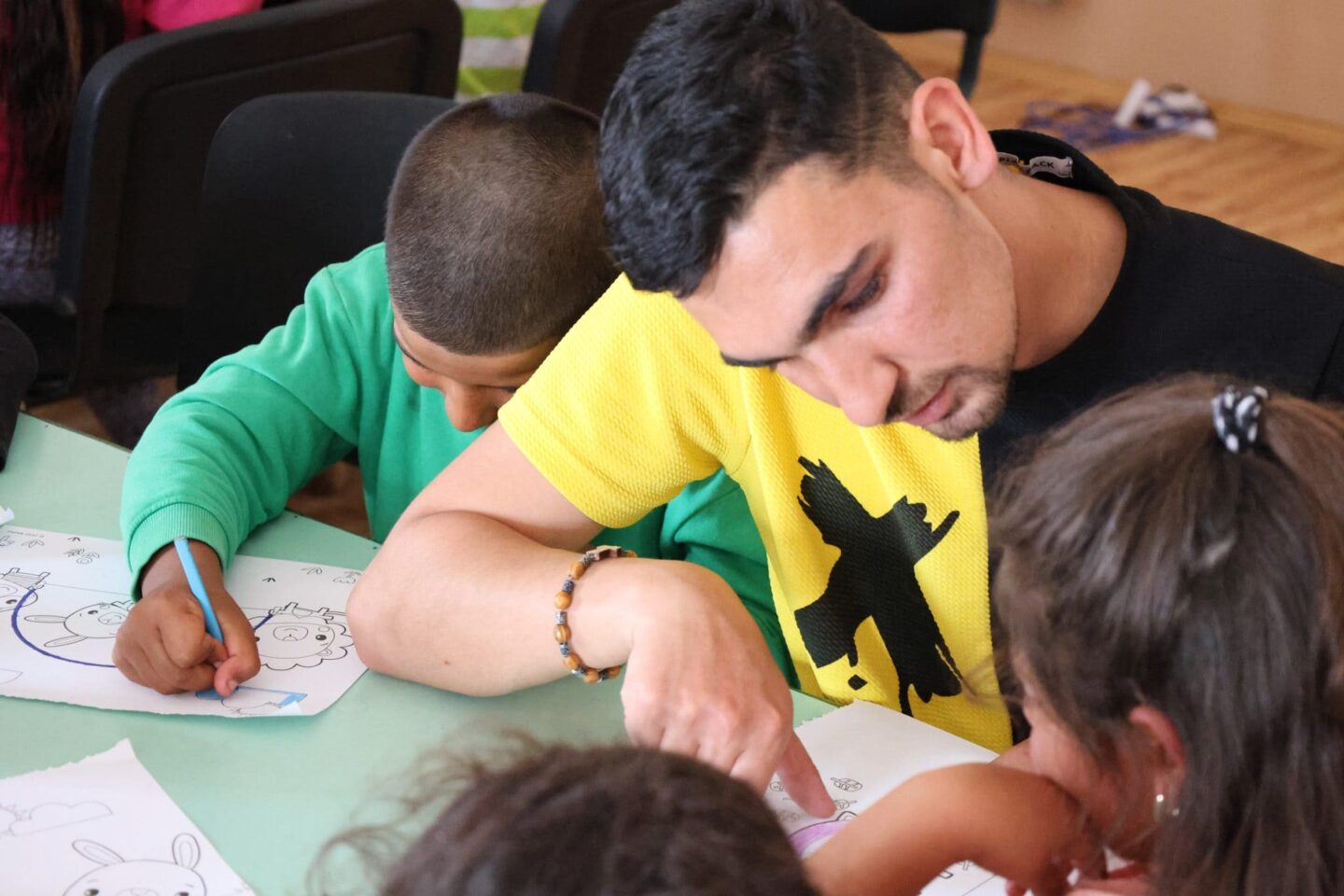 Muž si s deťmi kreslí pri stole