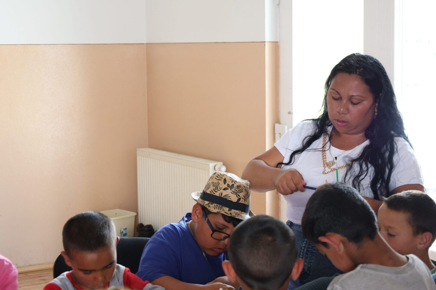 Rómske deti s pastoračnou pracovníčkou počas spoločného tvorenia pri stole