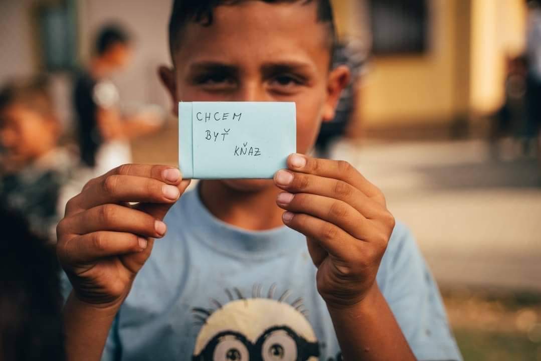 chlapec ukazuje lístok s nápisom chcem byť kňaz