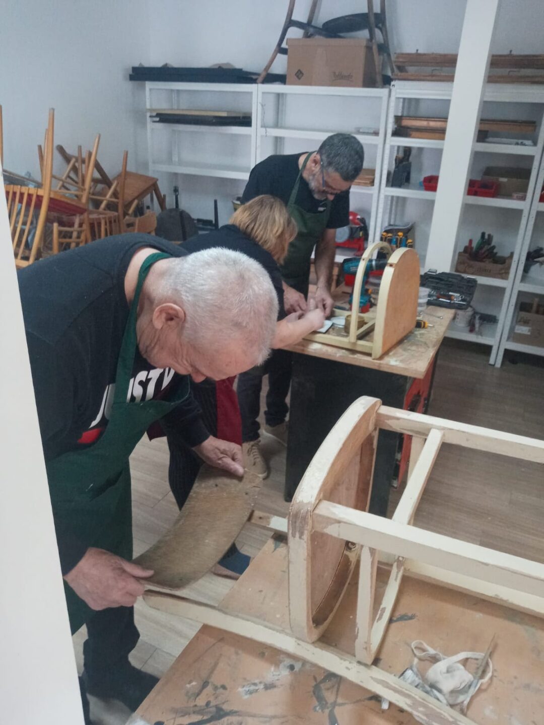 Dvaja muži a jedna žena opravujú stoličky
