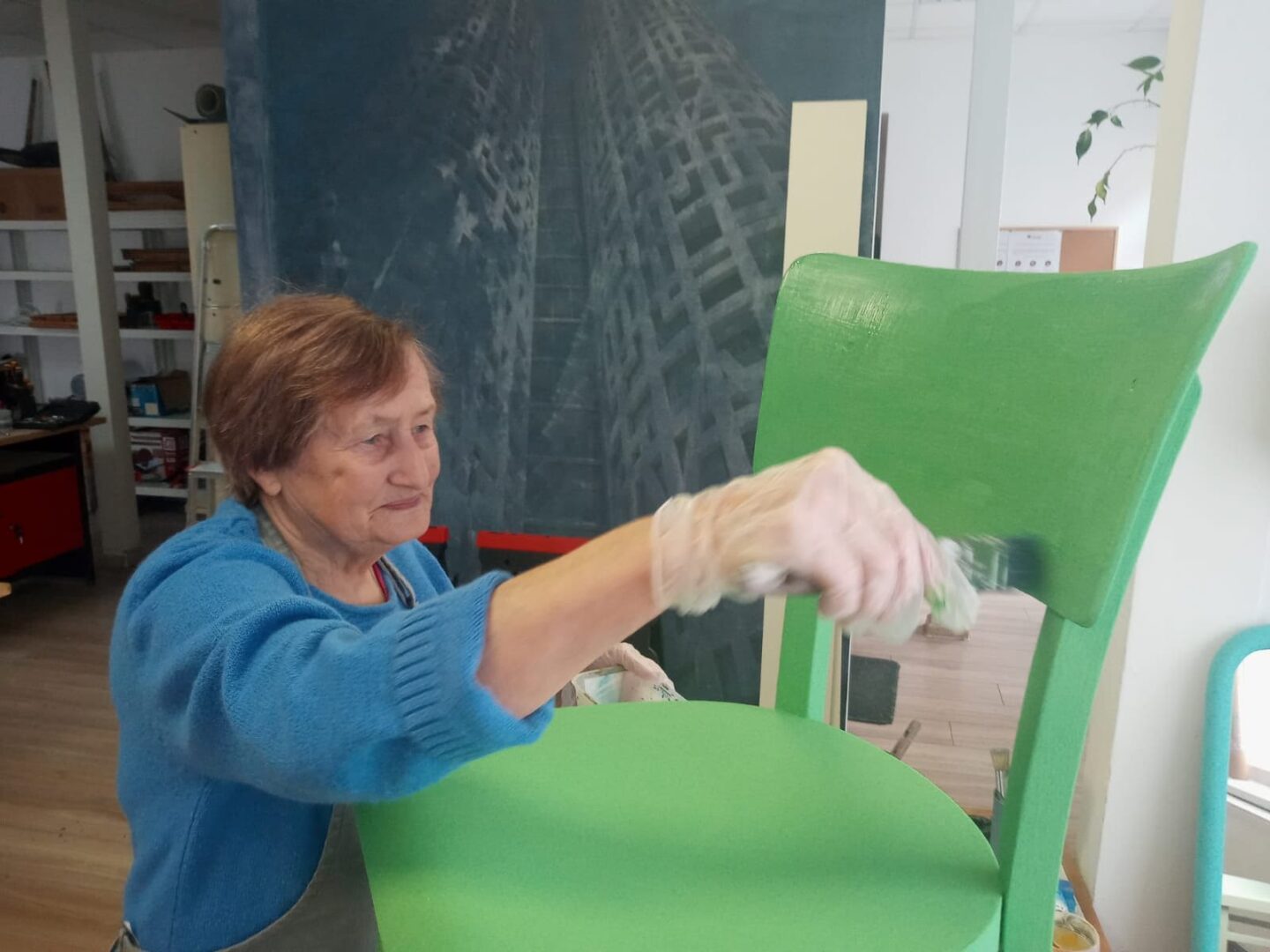 Žena natiera stoličku na zeleno