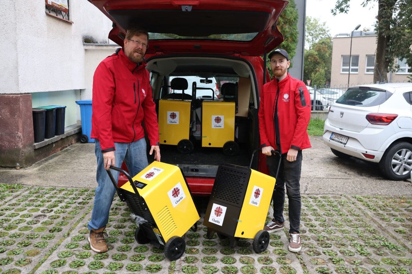 dvaja muži stoja pred autom so sušičmi