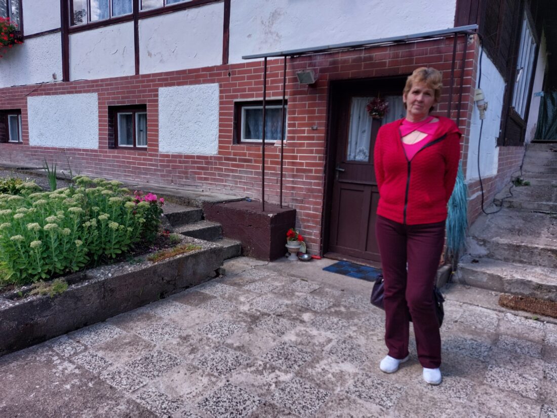 Žena stojí pred domom