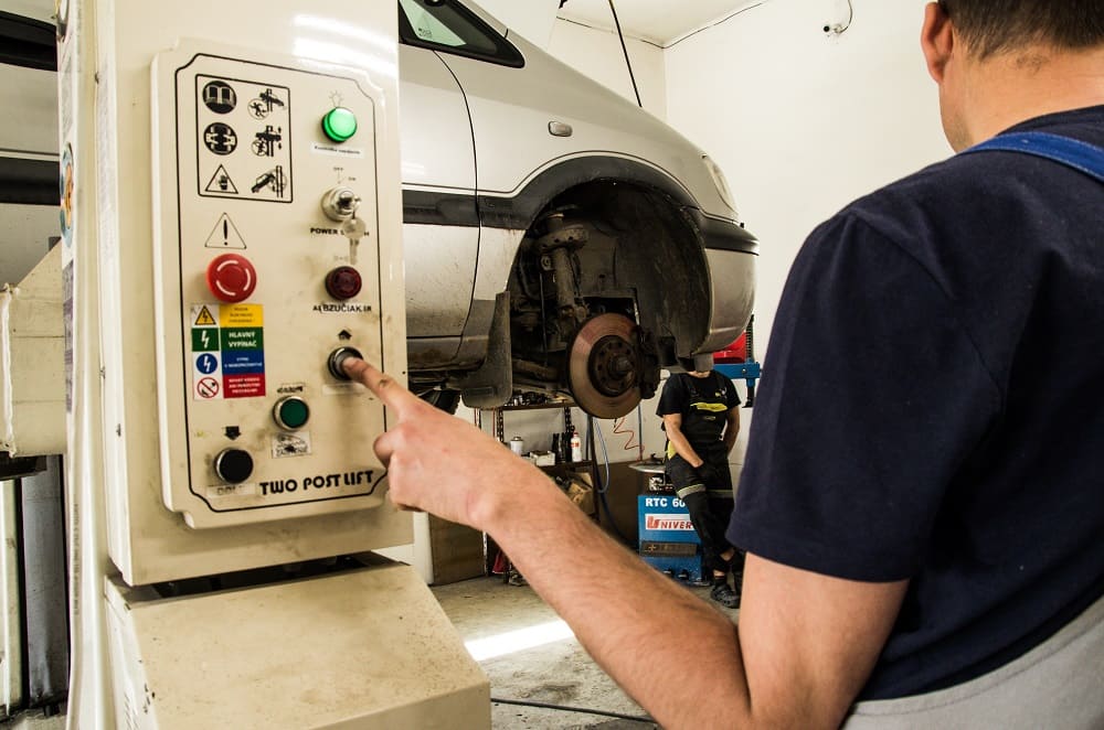 Muž stláča prístroj, ktorý pomáha opravit auto